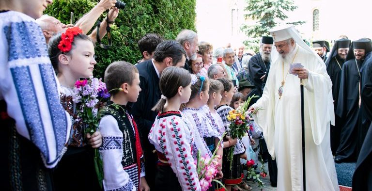 Cu dragoste părintească, binecuvântăm pe toţi elevii, părinţii, învățătorii și profesorii români de pretutindeni, la începutul anului şcolar 2021-2022. Sfântul Sinod al Bisericii Ortodoxe Române a declarat anul 2021 An omagial al pastoraţiei românilor din afara României. Prin slujitorii ei, Biserica Ortodoxă Română îi sprijină și încurajează pe credincioşii ortodocşi români din afara granițelor țării, înțelege bucuriile lor, dar și greutățile cu care aceștia se confruntă. Prin evenimentele culturale și acțiunile social-filantropice, organizate la nivelul Patriarhiei Române, se creează și se consolidează legături spirituale între comunități românești din țară și cele din diaspora română. Astfel, în perioada 21 decembrie 2020 – 22 august 2021, în Patriarhia Română s-a desfășurat Concursul Național Catehetic Biserica: familia românilor de pretutindeni, care s-a adresat copiilor din grupele catehetice parohiale din țară și din diaspora, înscrise în Programul Național Catehetic Hristos împărtășit copiilor. Grupurile de cateheză participante au realizat și au implementat miniproiecte având caracter cultural și filantropic, adresate cu preponderență familiei. Copiii și tinerii au fost totdeauna binecuvântaţi de Mântuitorul nostru Iisus Hristos, Învăţătorul desăvârșit, Care i-a preţuit (cf. Matei 14, 21), i-a ajutat (cf. Luca 7, 11-15; 8, 41-56), i-a primit cu dragoste (cf. Matei 19, 13-15; Marcu 10, 13-16; Luca 18, 15-17) și i-a ascultat cu atenţie (cf. Matei 19, 16-22). Urmând atitudinea lui Iisus, Biserica a înţeles că arta educației copiilor și a tinerilor nu este o lucrare oarecare, ci ea este cea mai însemnată dintre arte. În acest sens, Sfântul Ioan Gură de Aur spune: „Nu există nici o altă artă mai mare decât aceasta… căci ce este egal cu faptul de a armoniza sufletul și de a forma gândirea tânărului?” (Despre slava deșartă și cum trebuie părinții să–și crească copiii). Pandemia actuală a afectat în mod direct educația copiilor și a tinerilor. Studiile recente evidențiază utilitatea, dar și limitele educației on-line: stres, oboseală mentală, manifestări depresive, pierderea motivației, dificultăți în gândire, în concentrare și în luarea deciziilor. O educație temeinică pentru viață include experiențe nemijlocite, trăite în cadrul unei comunități concrete, începând din familie și continuând în Școală, în viața Bisericii și a societății. În contextul tradiției românești și europene, este cunoscut rolul determinant al Familiei și al Bisericii în educarea copiilor și a tinerilor de-a lungul timpului. Astăzi, când, sub influența unor ideologii secularizante, este diminuată contribuția acestora în domeniul educației, devine şi mai necesară cooperarea dintre Familie, Biserică și Școală, pentru a oferi copiilor și tinerilor ajutorul necesar dezvoltării lor atât în plan personal, cât şi comunitar. Cu prilejul începutului anului şcolar 2021-2022, ne rugăm lui Dumnezeu să îi ocrotească pe elevii, părinţii, învăţătorii şi profesorii români din România şi de pretutindeni, să le dăruiască sănătate şi mult ajutor, pace şi bucurie, pentru ca lucrarea lor să fie binecuvântare şi bucurie pentru Biserică, Familie și Societate! Cu multă preţuire şi părinteşti binecuvântări