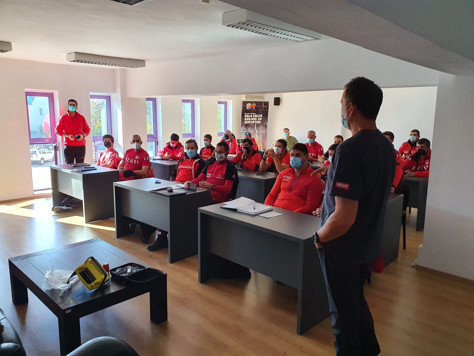 1.	Câți salvamontiști au participat la acțiune, câți dintre aceștia sunt sibieni? La exercitiul de formare cu aparatul Recco au participat 21 de salvamontisti din tara, cate 2 din fiecare judet ( Prahova, Arges, Maramures, Brasov, Mures, Alba, Bihor, Gorj, Suceava) iar de la Sibiu 2 salvamontisti si eu, in calitate de organizator cat si de salvator montan  2. Descrie, te rog,  importanța, utilitatea acestui aparat? Cum vă poate ajuta el mai repede sau mai bine în acțiunile de căutarea a persoanelor? Sistemul RECCO, este format dintr-un dispozitiv de localizare utilizat de salvamontiști și plăcuțe reflectoare pe care turiștii le pot purta în echipamente și cu ajutorul cărora este posibilă găsirea acestora. Detectorul poate localiza plăcuțele reflectoare pe o rază de până la 80 de metri în aer și 20 de metri la sol, respectiv o rază efectivă de 30 de metri în condiții de avalanșă. Sistemul este în prezent folosit de 900 de organizații de salvatori montani și resorturi de schi din 28 de țări din toată lumea. 3. Cât timp au durat acele cursuri? Cursul de pregatire cat si exercitiul a durat o zi. Prima parte a fost alocata cursului teoretic, iar a doua parte a constat in pregatirea efectiva a salvatorilor montani in utulizarea aparatului si gasirea unor placute Recco. 4. Sibiul deține acest aparat de 10 ani, câte intervenții ați avut cu acestea și cum va ajutat în salvarea vieților? Dacă poți să îmi dai și exemple concrete, ar fi și mai bine Spj Salvamont Sibiu a fost solicitat de-a lungul anilor, de catre formatii din intreaga tara, pentru gasirea unor persoane disparute in avalansa. Din pacate niciuna dintre victime nu avea imbracaminte cu acesta tehnologie, dar am reusit sa gasim semnal care a venit de la echipamentele turistilor, astfel am restrans zona de cautare, ulterior fiind gasiti prin sondare. In zonele de offpiste turistii ar trebui sa fie echipati cu echipament complet ( dispozitiv DVA, sonda, lopata). Acestea sunt un minim de echipament obligatoriu. Tehnologia recco are avantajul ca nu are nevoie de baterii pentru a emite, se afla in permanenta integrat in echipament, deci nu poate fi uitat acasa, facandu-l un sistem complementar si iti mareste sansele sa fi gasit in cazul in care ai fost surprins de avalansa.